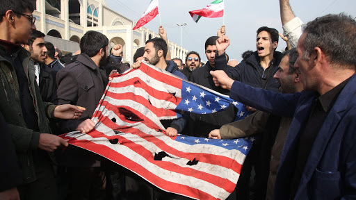 Iranians tear up a US flag during a demonstration in Tehran on January 3, 2020 following the killing of Iranian Revolutionary Guards Major General Qasem Soleimani in a US strike on his convoy at Baghdad international airport. - Iran warned of severe revenge and said arch-enemy the United States bore responsiblity for the consequences after killing one of its top commanders, Qasem Soleimani, in a strike  outside Baghdad airport. (Photo by ATTA KENARE / AFP) (Photo by ATTA KENARE/AFP via Getty Images)