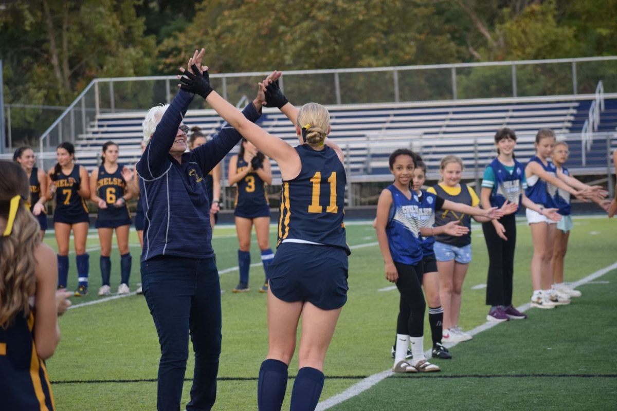 Rowan Burkle gets leaps up to high five her coach to get hype for a game as she has 2 teams there for her in support
